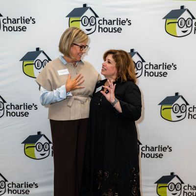 Two women laughing together at the Charlie's House backdrop