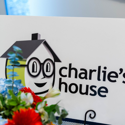 Charlie's House logo sign behind a bouquet of red and orange flowers