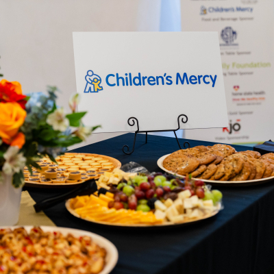 Food table with fruit, cheese and cookies beside a Children's Mercy sponsor sign