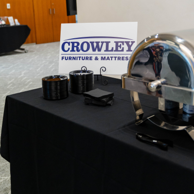 Buffet table with a chafing dish and a Crowley Furniture & Mattress sign