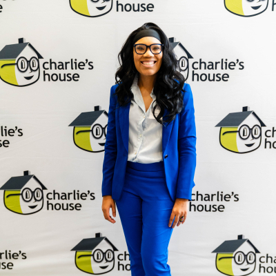 Woman in a blue suit posing at the Charlie's House photo backdrop