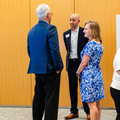 Three guests in conversation against a wood-paneled wall