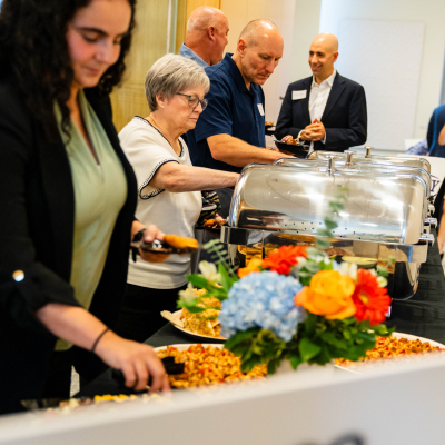 Guests filling plates at the buffet decorated with fresh flowers