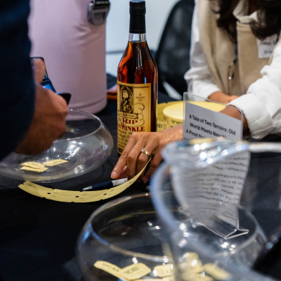 Close-up of raffle tickets in glass bowls beside a bottle of bourbon