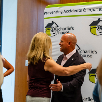 Guest hugging a man in front of a Charlie's House step-and-repeat banner