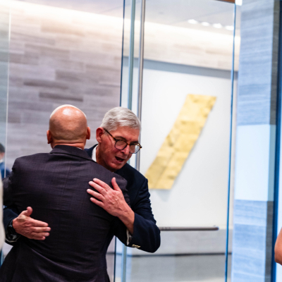Two men sharing a warm hug at the anniversary event