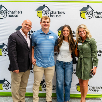 Family of four posing for a full-length photo at the Charlie's House banner