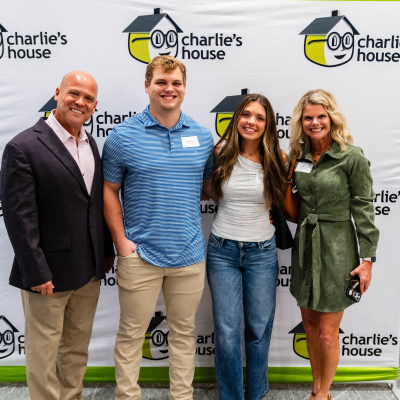 Four guests posing together at the Charlie's House photo backdrop