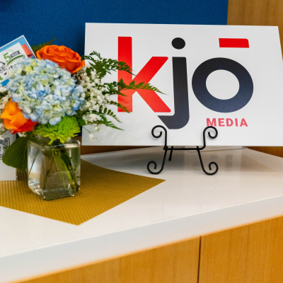 KJO Media sponsor sign beside a floral arrangement