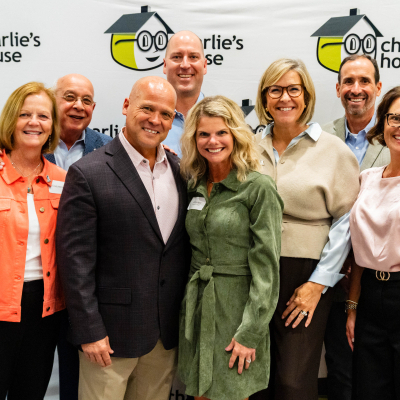 Close-up group photo of guests smiling at the Charlie's House backdrop