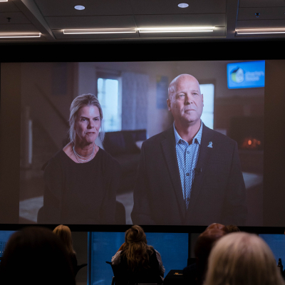 Audience watching a video of a man and woman projected on the big screen