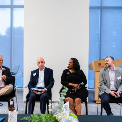 Four panelists seated in front of tall windows during the discussion