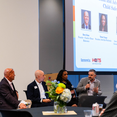 Panel of four speakers in front of a screen about advocacy work for child safety