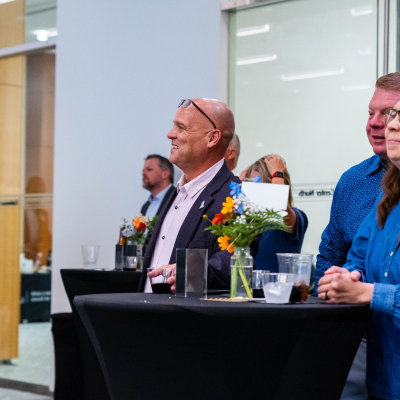 Guests at a cocktail table smiling as they watch the program