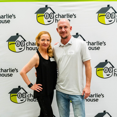Man and woman standing together at the Charlie's House photo backdrop