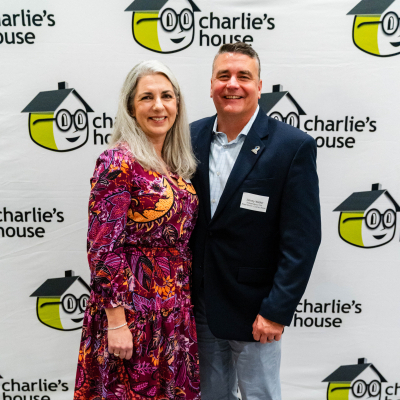 Couple standing together for a full-length photo at the Charlie's House backdrop