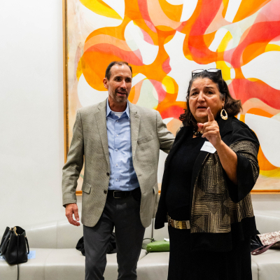 Woman giving a thumbs up beside a man in front of a colorful abstract painting