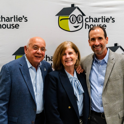 Three guests smiling together at the Charlie's House photo backdrop