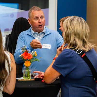 Man looking surprised while chatting with guests at a cocktail table