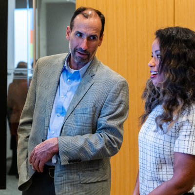 Man in a tweed blazer talking with a woman in a checked dress