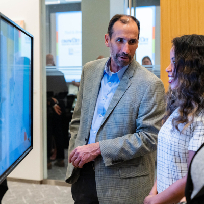 Man in a tweed blazer standing beside the safety display while talking with guests