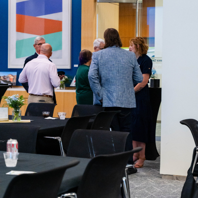 Guests chatting near the tables in the event room before the program
