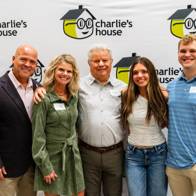 Group of five guests smiling at the Charlie's House photo backdrop