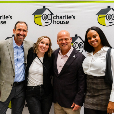 Four guests smiling together at the Charlie's House photo backdrop