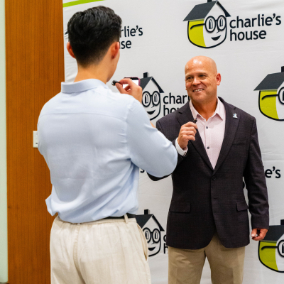 Man smiling while being recorded at the Charlie's House banner