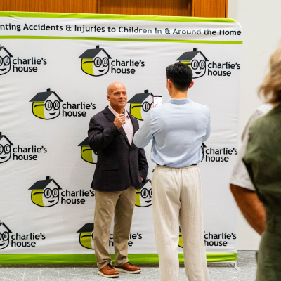 Two men talking in front of the Charlie's House banner, seen from behind