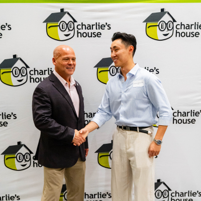 Two men shaking hands at the Charlie's House photo backdrop