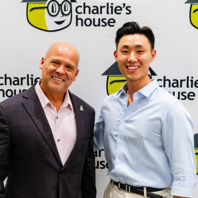 Close-up of two smiling men at the Charlie's House photo backdrop