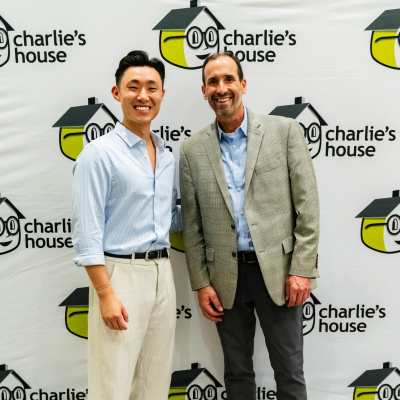 Two men posing for a photo at the Charlie's House backdrop
