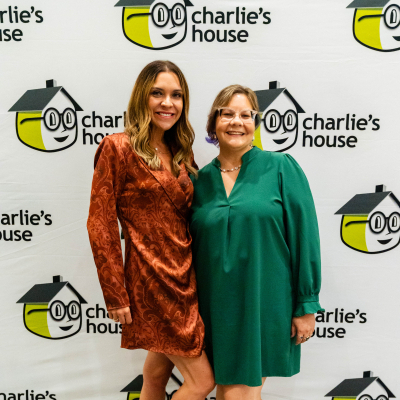 Two women posing together at the Charlie's House photo backdrop
