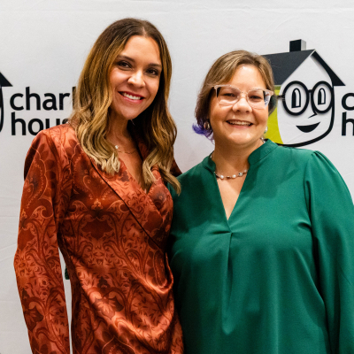 Two women smiling in front of the Charlie's House logo backdrop