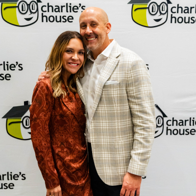 Couple posing in front of the Charlie's House step-and-repeat banner
