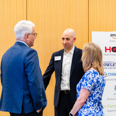 Three guests talking beside a sponsor banner