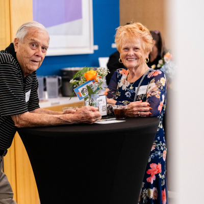 Older couple smiling at a cocktail table at the reception