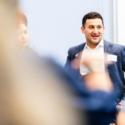 Smiling man in a navy blazer standing among guests at the reception