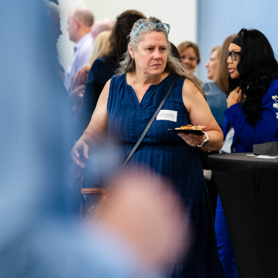 Guest in a blue dress holding a plate while mingling at the reception