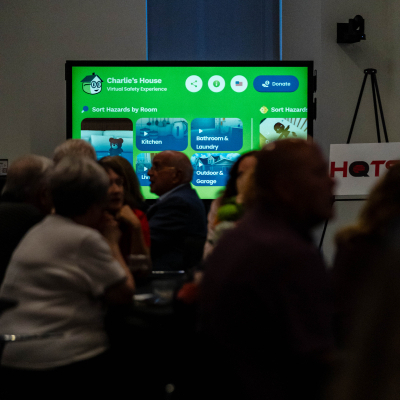 Audience viewing the Charlie's House website displayed on a screen near a HOTS sign