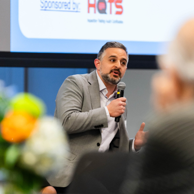 Close-up of a panelist in a gray blazer speaking into a microphone during the discussion