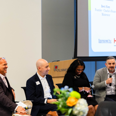 Panelists laughing together on stage as one speaks into a microphone