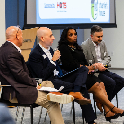 Four panelists listen as one speaks into a microphone at the Charlie's House anniversary event