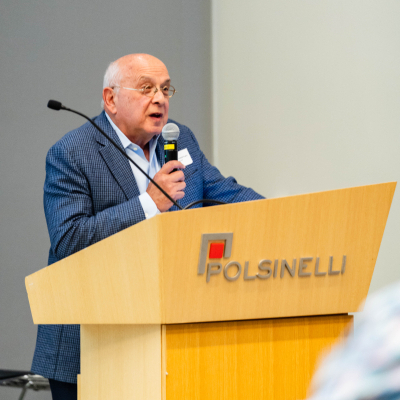Older man in a blue blazer speaking at the Polsinelli podium