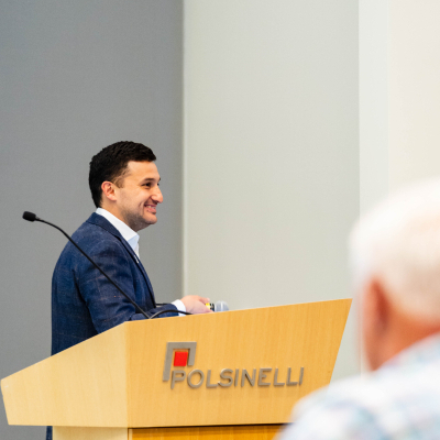 Speaker smiling at a Polsinelli podium while addressing guests